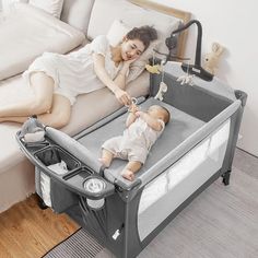 a woman laying on top of a bed next to a baby in a crib