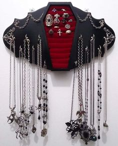 a black and red wall hanging with lots of silver jewelry on it's sides