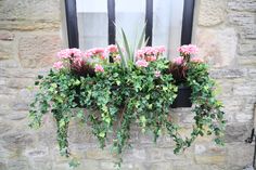 a window box filled with red flowers and greenery