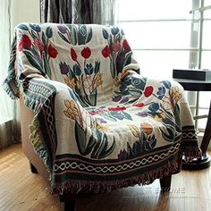 a chair with a blanket on top of it in front of a window and wooden floor