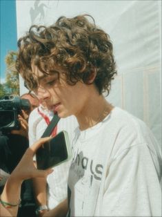 a young man with curly hair holding a camera