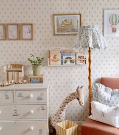 a baby's room with a giraffe toy next to a dresser and bed