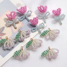 six different colored beaded butterfly charms sitting on top of a white table next to a card