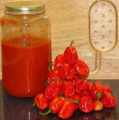 some red peppers sitting on a counter next to a jar of ketchup