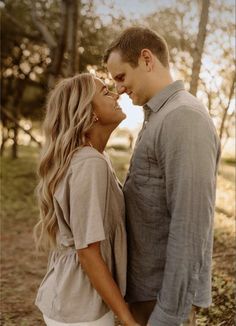 a man and woman standing next to each other in front of trees with the sun shining on them