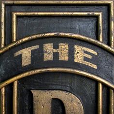 the letter d is carved into an old door with gold and black paint on it