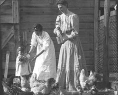 an old black and white photo of two women feeding chickens