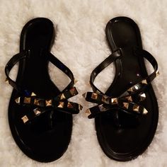 Black Thong Bow Sandals With Gold Spikes On The Bow And Sides. One Spike Is Missing On The Right Sandal. New In Package Without Tag. Trendy Black Toe Post Flip Flops, Black Toe Post Flip Flops For Beach Season, Black Flip Flops For Beach, Black Open Toe Flip Flops For Beach, Black Open Toe Flip Flops For Beach Season, Black Flat Flip Flops For Summer, Black Jelly Sandals For Summer Party, Black Jelly Sandals For Summer, Black Beach Flip Flops