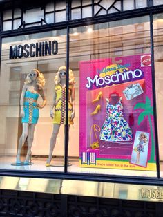 two mannequins are displayed in the window of a clothing store on moschino street