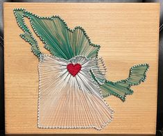 a piece of art made out of string and wood with a red heart on it