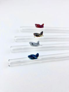 four glass birds sitting on top of each other in the middle of a white surface