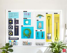 a white pegboard with lots of tools on it next to a potted plant