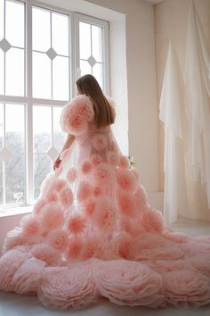 a woman standing in front of a window wearing a dress made out of pink flowers