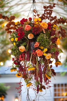 an arrangement of flowers hanging from a chandelier with lights in the back ground