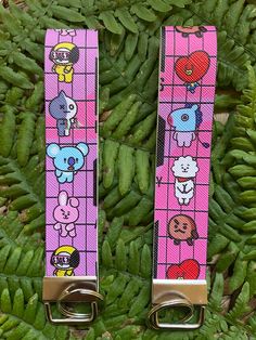 two pink straps with cartoon characters on them are sitting in the grass next to green plants