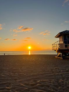 a lifeguard tower on the beach at sunset