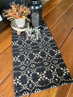 a black and white table runner on a wooden floor next to a potted plant