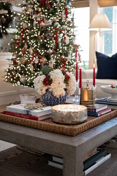 a living room with a christmas tree in the background and candles on the coffee table