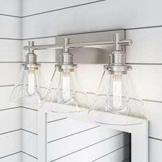 two light bathroom fixture with clear glass shades on the mirror and white paneled wall