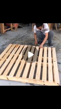 a man kneeling down on top of a wooden pallet