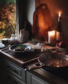 two pans on a stove with food in front of them and a lit candle