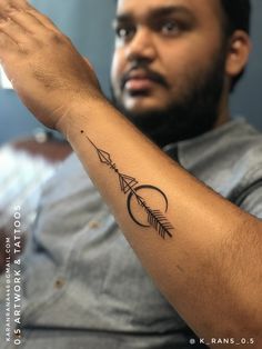 a man with a tattoo on his arm holding an arrow in the palm of his hand