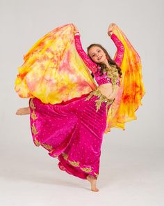 a woman is dancing with an orange and yellow shawl