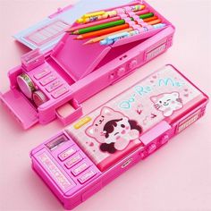 a pink toy cell phone sitting on top of a table next to a case with pens and pencils in it