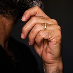 a close up of a man holding his hand to his face with a ring on it