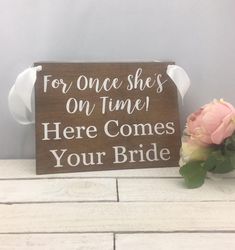 a sign that says for once she's on time here comes your bride next to a flower