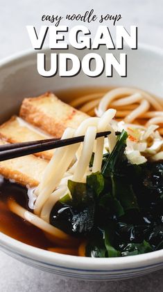 a bowl filled with noodles and vegetables next to chopsticks in broth sauce