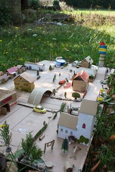 a model train set in the middle of a field with cars and buildings on it