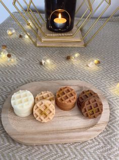 three waffles sitting on a wooden plate next to a candle and some candles