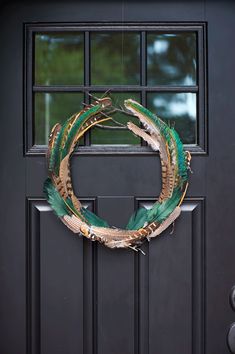 a wreath made out of feathers is hanging on the front door's black door