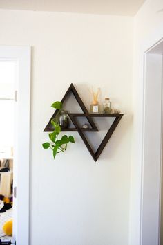 a wall mounted shelf with two shelves and a plant on it, in the corner of a room