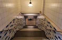 an escalator with blue and white tiles on the wall next to a stair case