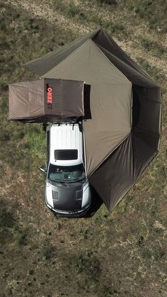 an overhead view of a tent with a car under it in the middle of nowhere