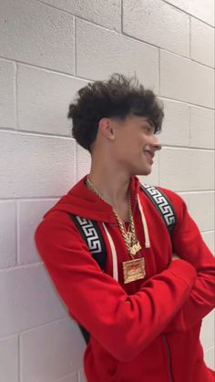 a young man in a red hoodie leaning against a wall