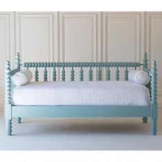 a blue daybed with two pillows on the top and bottom, against a white wall