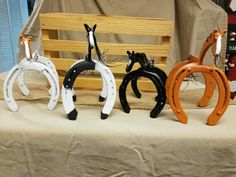 three different colored horseshoes sitting on top of a white tablecloth covered table next to a wooden bench