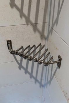 a metal rack in the corner of a tiled shower stall with no curtain on it