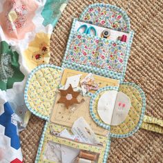 sewing supplies laid out on the floor next to some fabric and paper pieces that have been sewn together