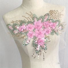 a white mannequin with pink flowers on it's chest and beading