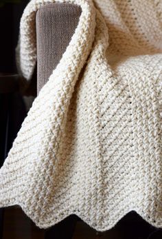 a white crocheted blanket sitting on top of a chair