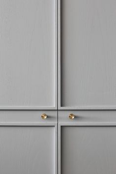 two white cupboards with gold handles and knobs on the doors, one is painted gray