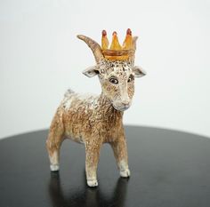 a statue of a goat wearing a crown on top of it's head and standing on a table