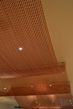 the ceiling is made up of orange mesh and has lights hanging from it's sides