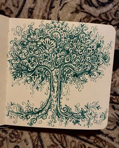 an open notebook with a drawing of a tree on the cover and swirly designs