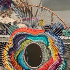 a large circular basket with many different colored yarns in it and a mirror hanging on the wall