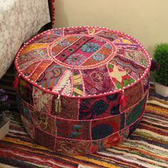 a colorful patchwork ottoman sitting on top of a rug next to a potted plant